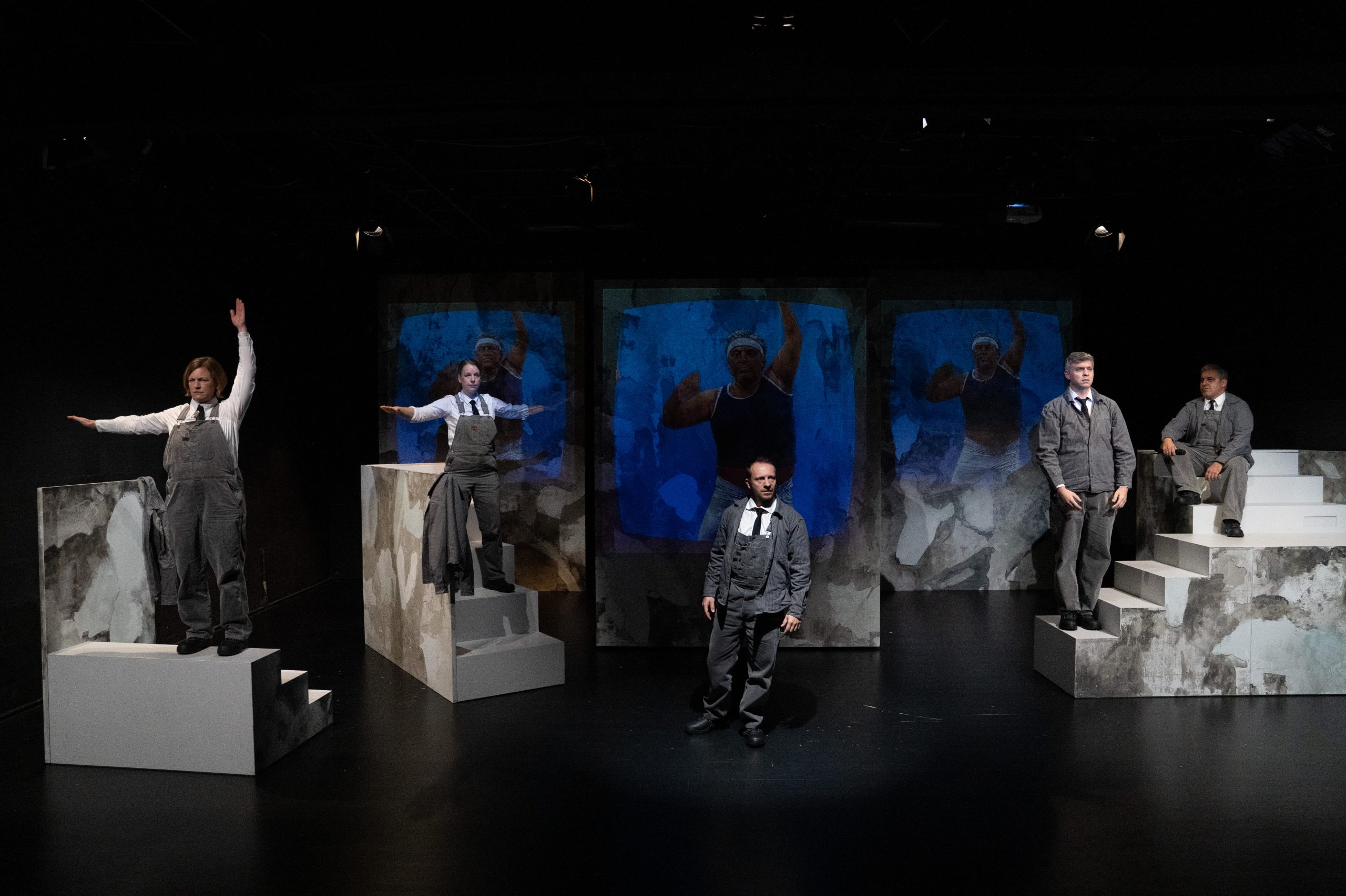 Verschiedene Menschen auf einer Bühne, im Hintergrund eine Projektion