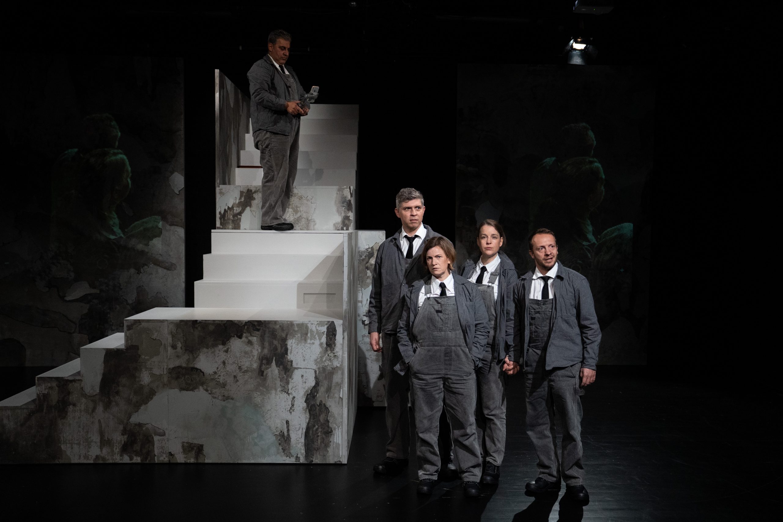 Vier Menschen stehen neben einer Treppe und beobachten etwas, das man nicht sehen kann