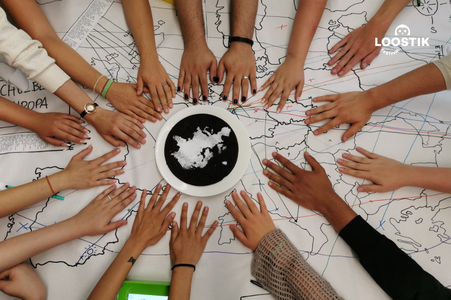 Viele Hände liegen im Kreis auf einer Landkarte