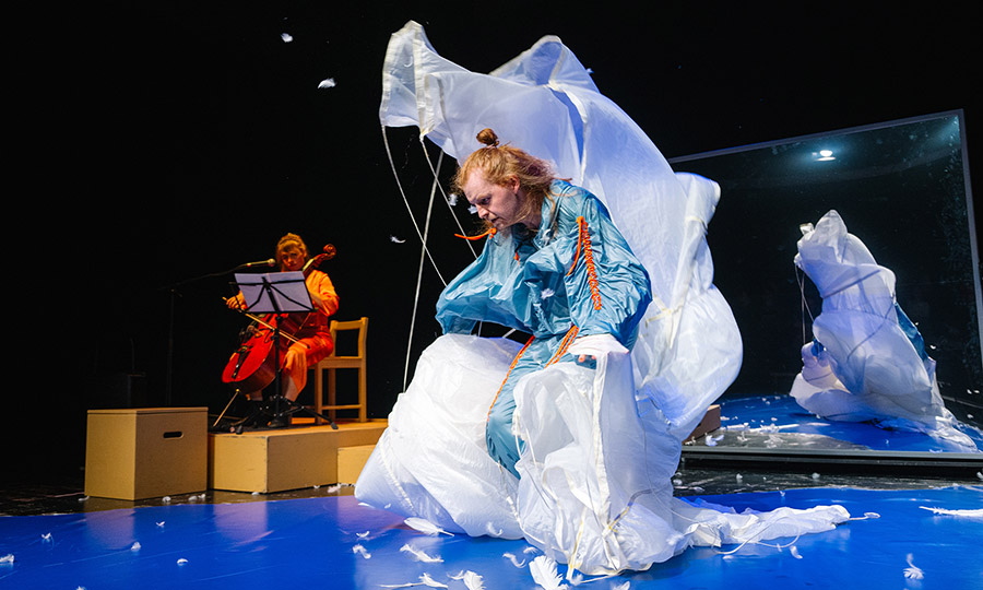 Eine Person in blauem Trainigsanzug spielt mit einem großen Gebilde aus weißem Stoff