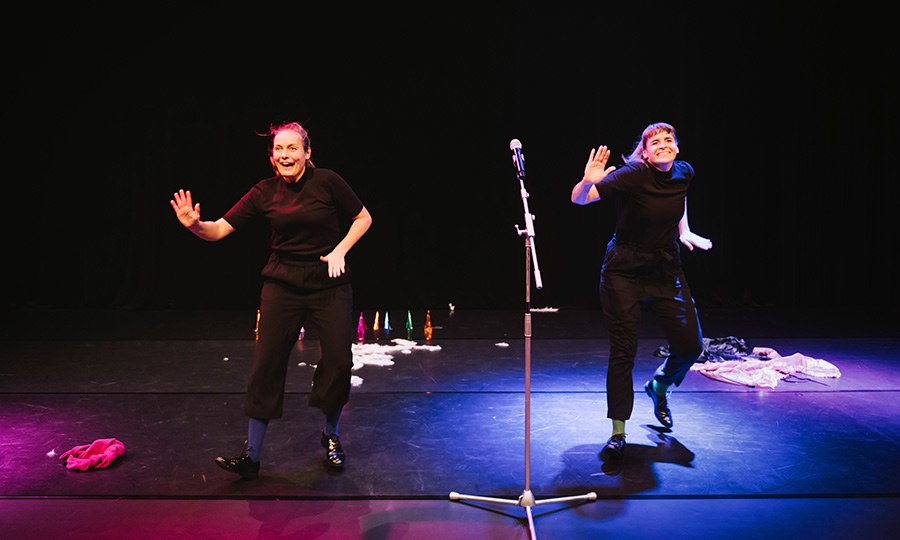 Zwei Personen in schwarzer Kleidung tanzen auf einer Bühne