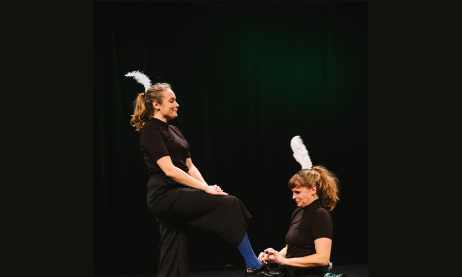 Eine Person kniet vor einer anderen und bindet ihr den Schuh