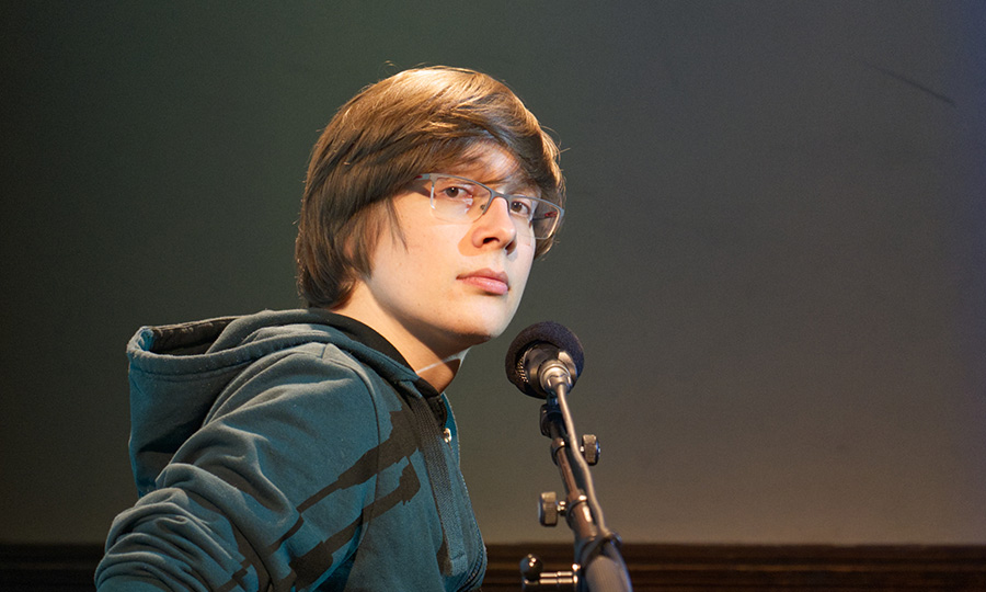 Eine Person mit Mikrofon schaut seitlich in die Kamera