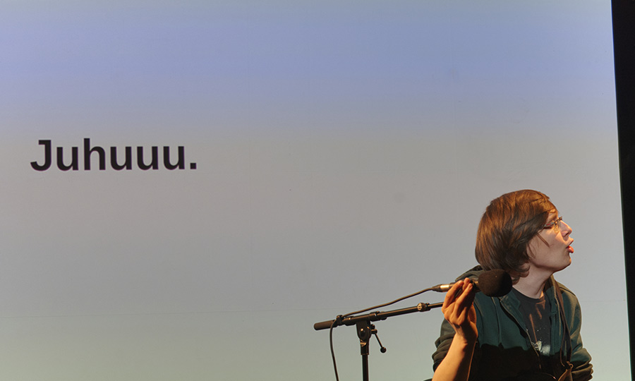 Eine Person vor einer Leinwand, auf der "Juhuuu" steht