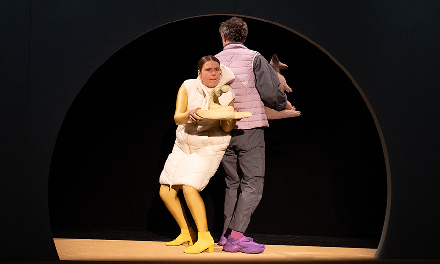 Zwei Personen stehen Rücken an Rücken. Eine Person hält eine Schlange aus Pappmaché, die andere ein Gürteltier aus Pappmaché.